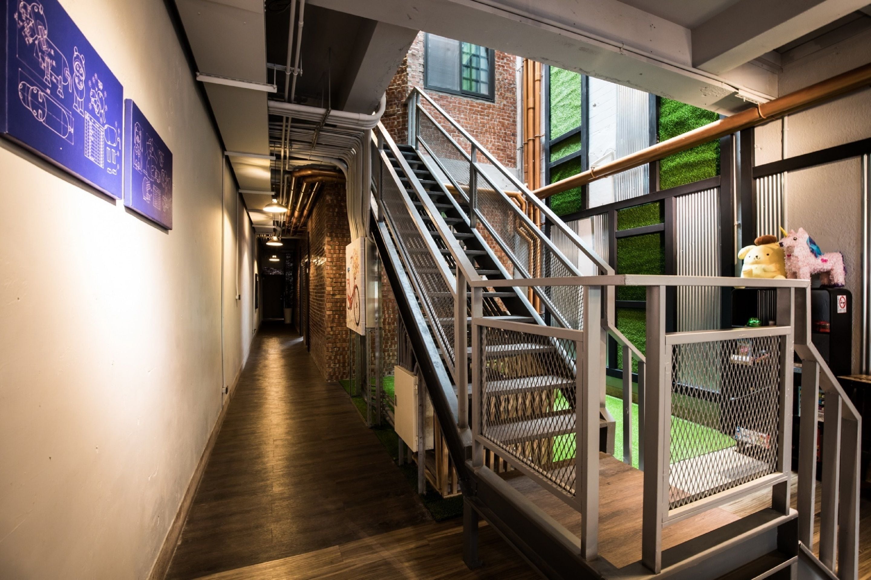 A corridor with a staircase leading to a balcony with a view of a green outdoor area.