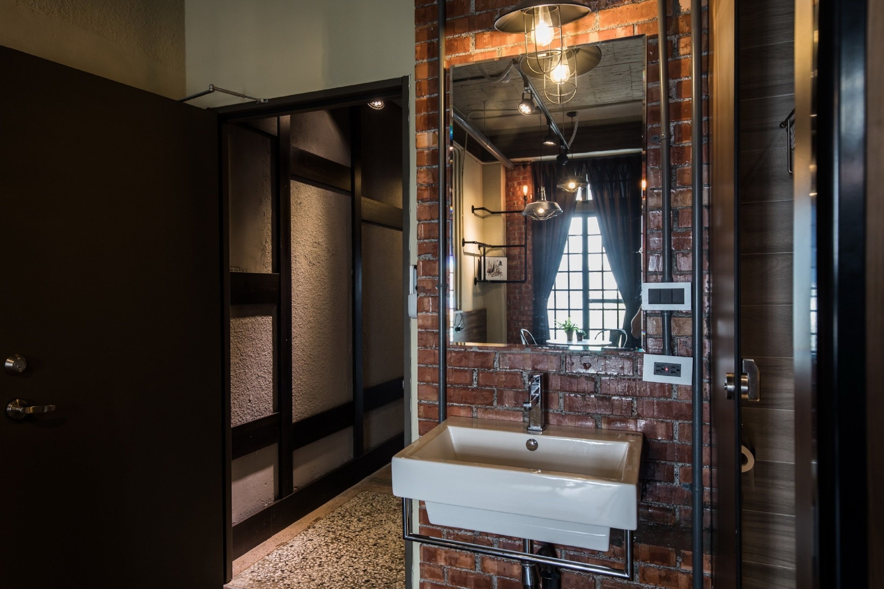 Une salle de bain moderne avec un grand miroir, un lavabo blanc et un mur en briques.