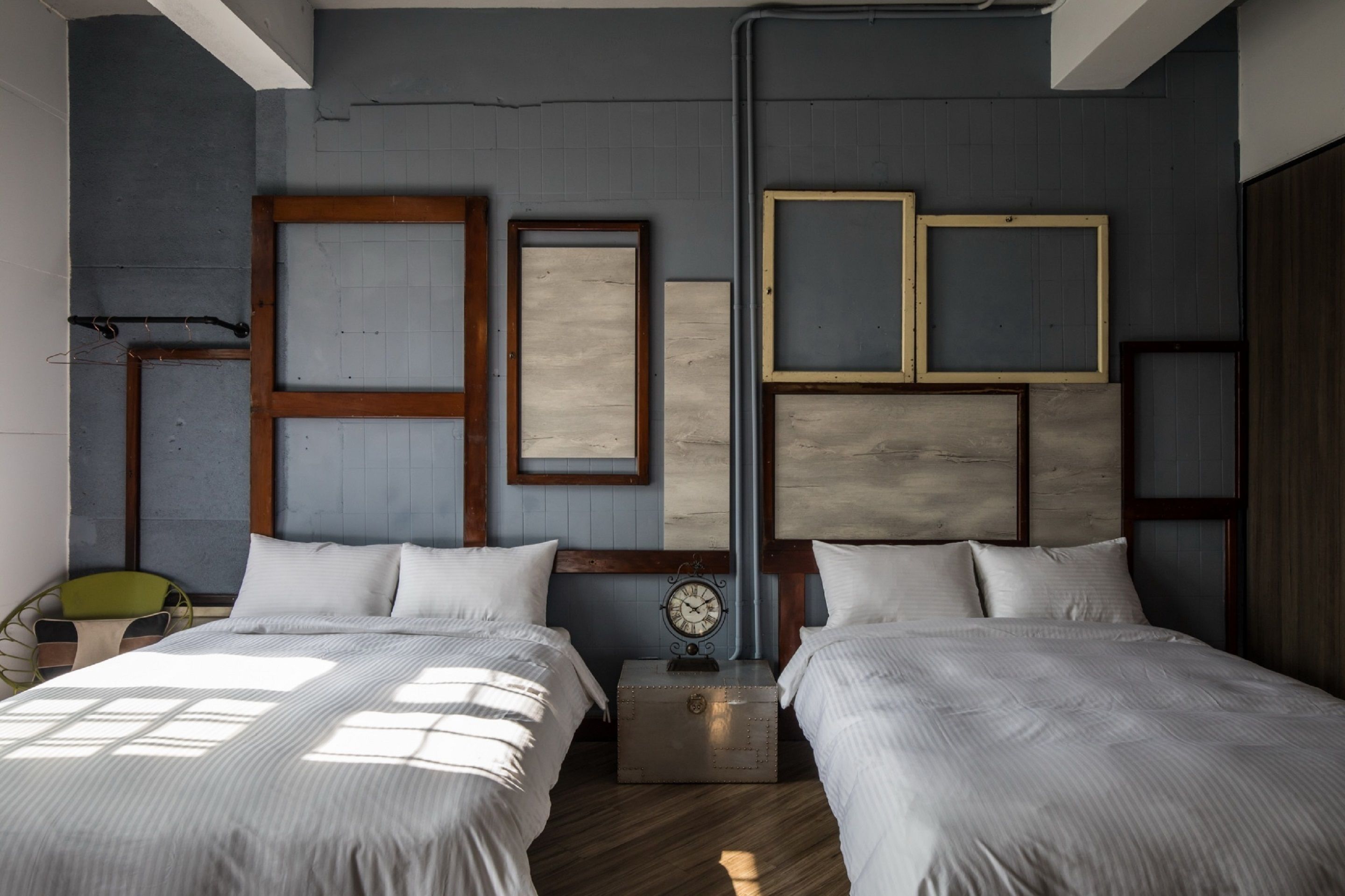 A bedroom with two beds, a clock, and framed pictures on the wall.