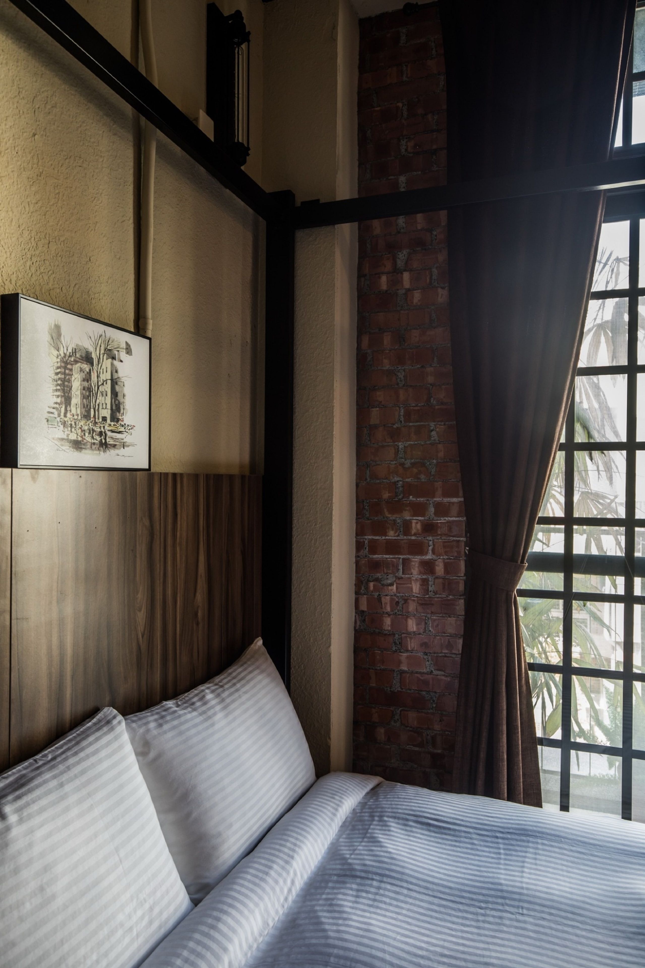 Ein Hotelzimmer mit einem großen Bett, einer Backsteinwand und einem Fenster mit Vorhängen.