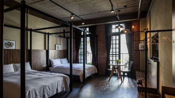 Ein Hotelzimmer mit zwei Betten, einem kleinen Tisch und einer Hängelampe.