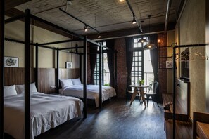 A hotel room with two beds, a small table, and a hanging light fixture.