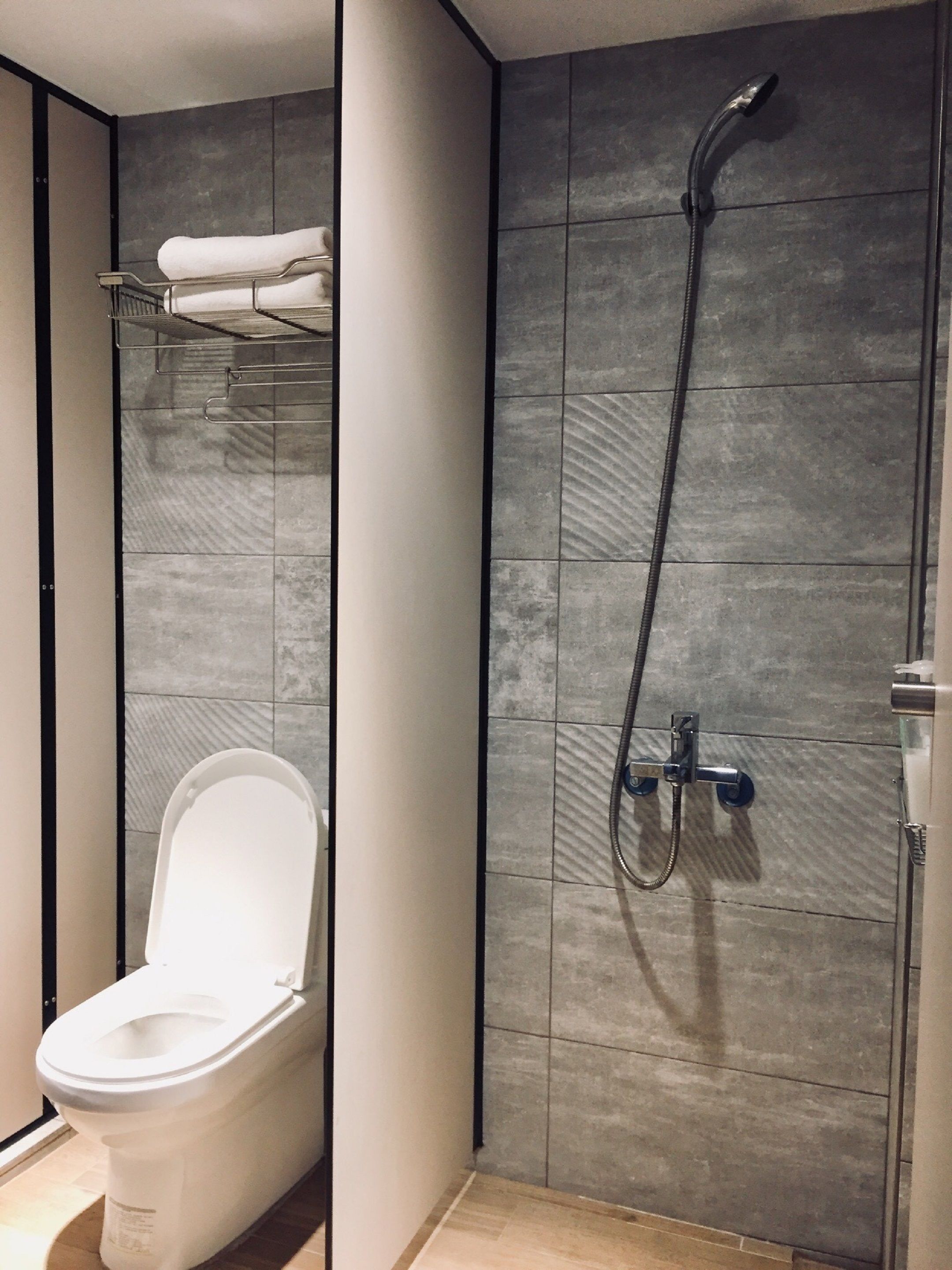 A modern bathroom with a toilet, a shower, and a towel rack.
