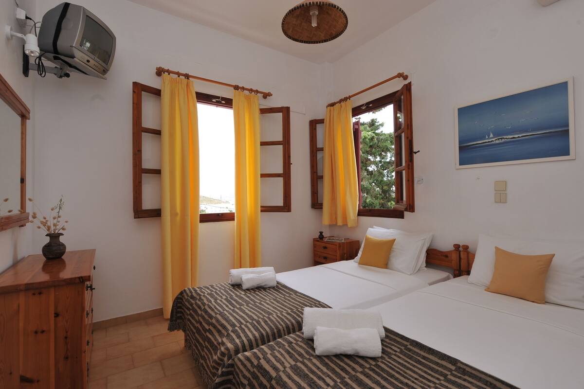 A hotel room with two beds, a TV, a painting, and a wooden dresser.