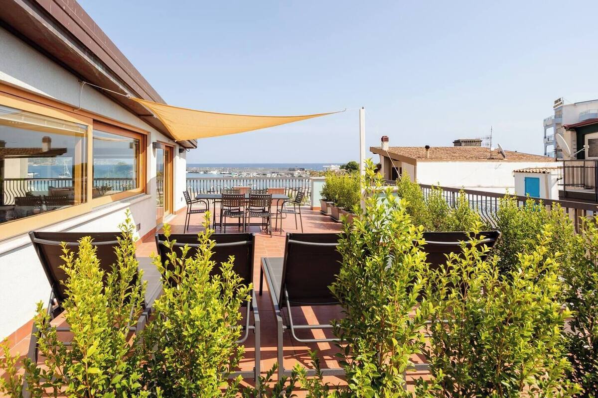 Eine Terrasse mit Sitzgelegenheit, Meerblick und ein Gebäude mit Balkon.