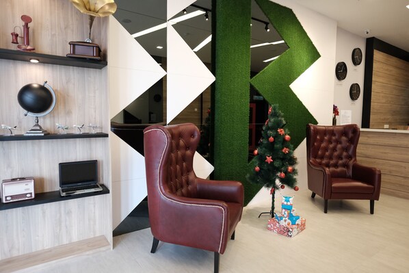Una moderna zona de recepción con sillones de cuero, un árbol de Navidad y un escritorio con una computadora portátil y un radio.