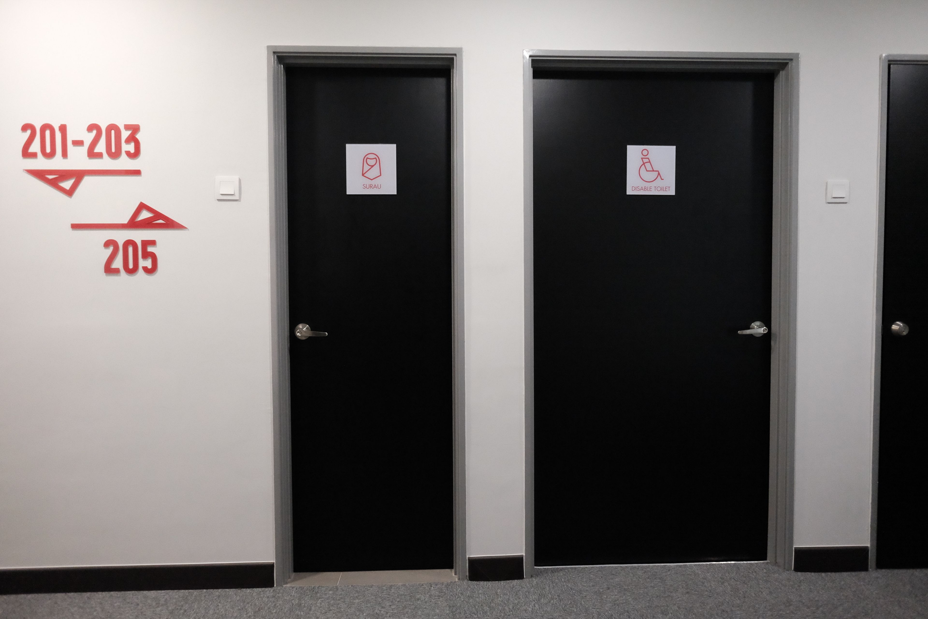 Three black doors with signage indicating room numbers 201-203 and 205, and a disabled toilet sign.