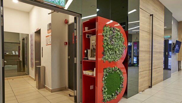 Un interno moderno con un bancone rosso, decorazioni verdi al muro e un ascensore in vista.