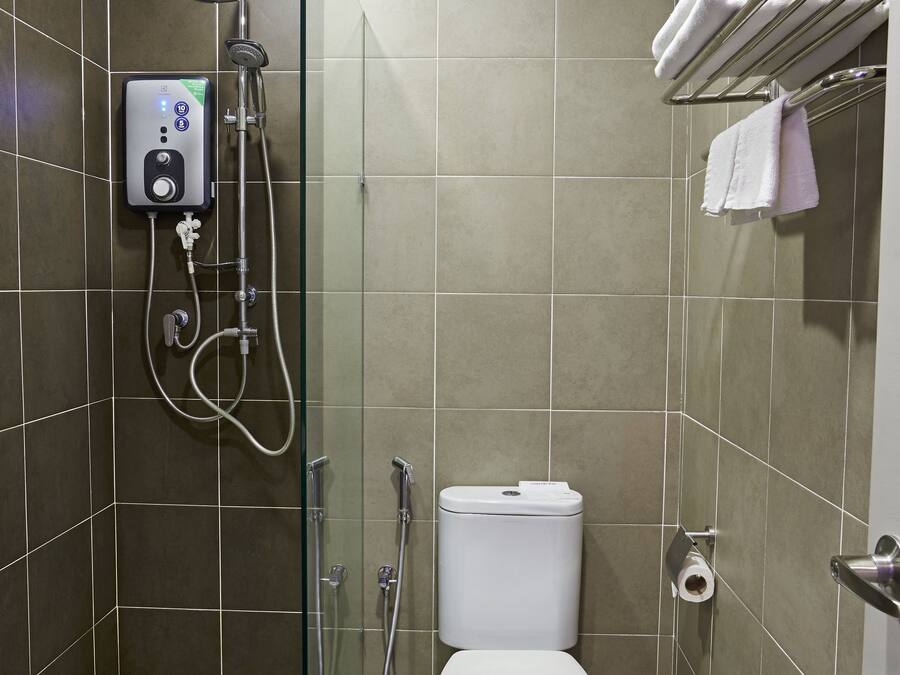 A modern bathroom with a glass-enclosed shower, a toilet, and a towel rack.