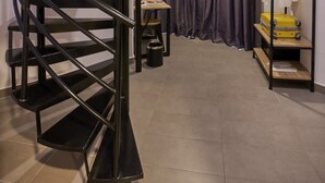 Una moderna scala a chiocciola dal design minimalista, un piccolo tavolo con una sedia e uno scaffale con una valigia e una pianta.