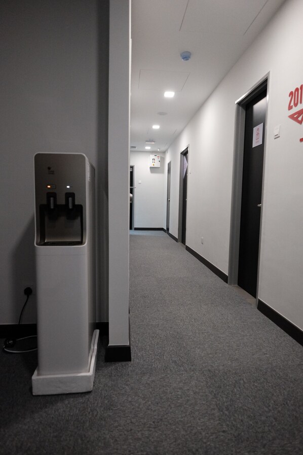A hallway with a water dispenser, a fire alarm, and a door marked with the year 2011. - B Lot Hotel (Kuala Lumpur)