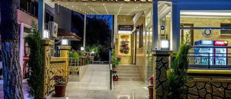 The entrance of Kayı Butik Hotel with a well-lit facade, a staircase leading to the entrance, and potted plants along the pathway.