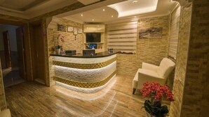 A reception area with a curved counter, a white armchair, and a vase of flowers. - Kayi Hotel (Fethiye)