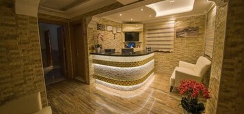 A reception area with a curved counter, a white armchair, and a vase of flowers.