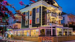 A multi-story hotel with balconies, a covered outdoor seating area, and a view of the street. - Kayi Hotel (Fethiye)