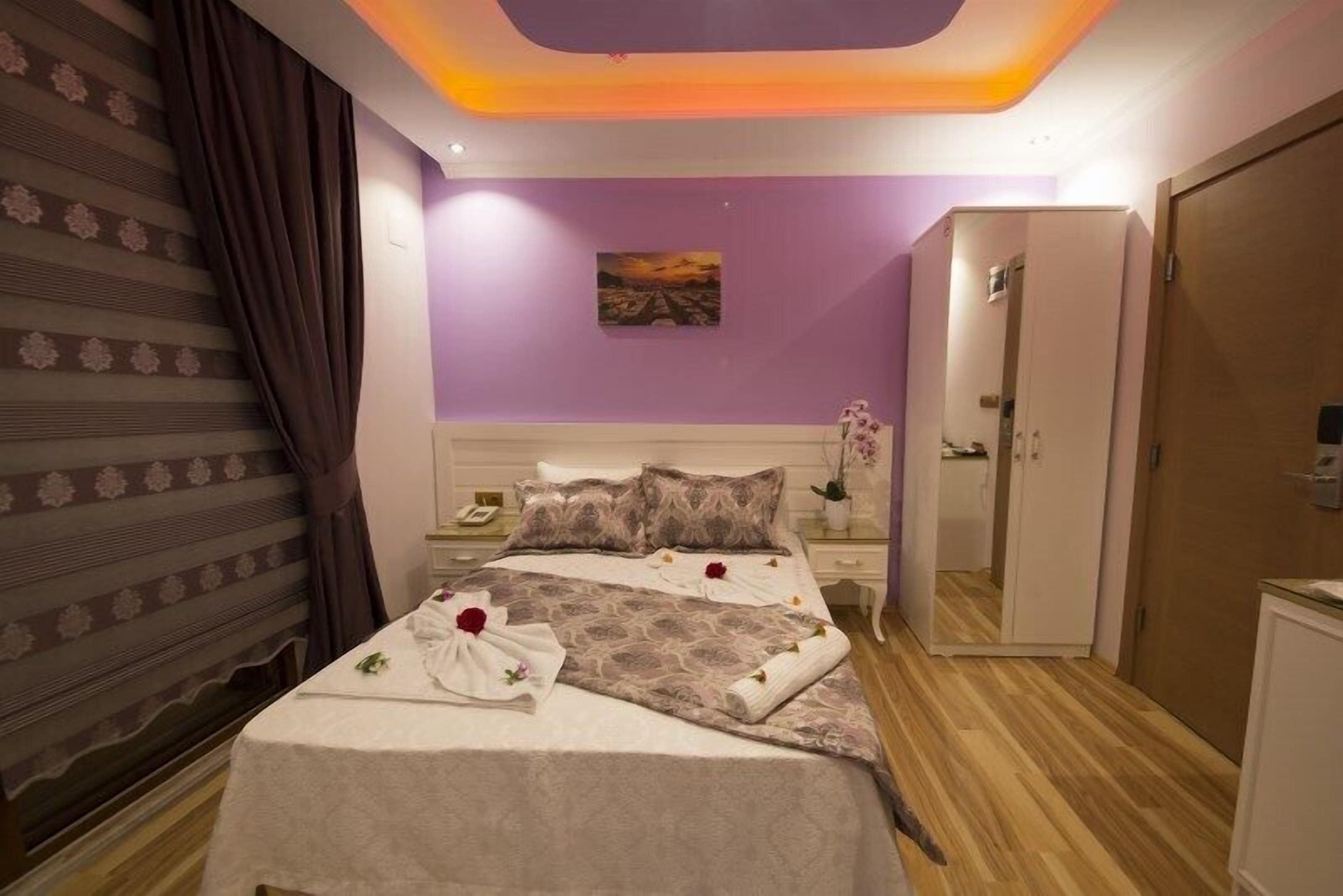 A hotel room with a bed, a nightstand, a painting on the wall, and a door.