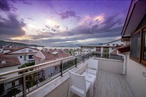 A balcony with a view of a cityscape during sunset.