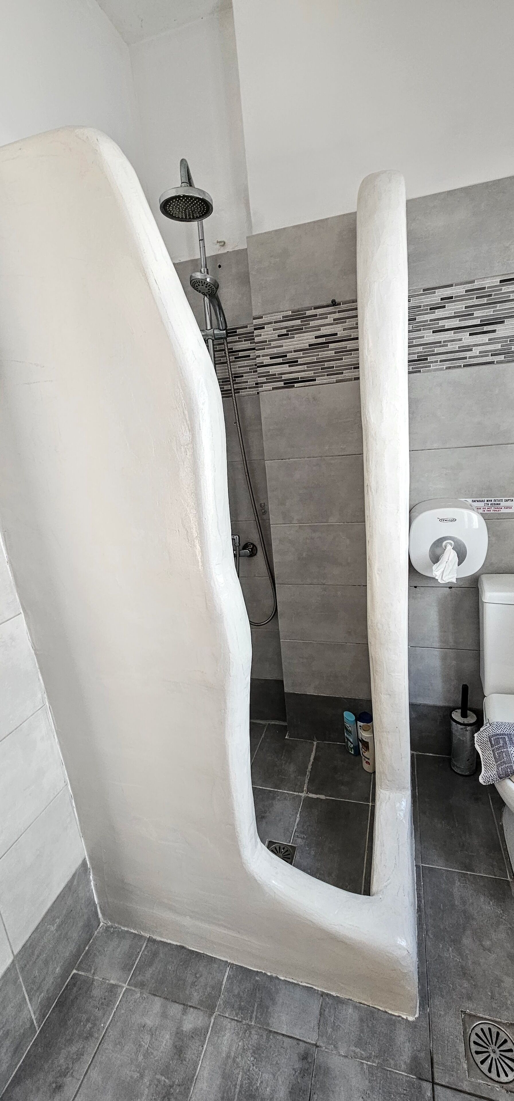 Een badkamer met douche, toilet en betegelde vloer.