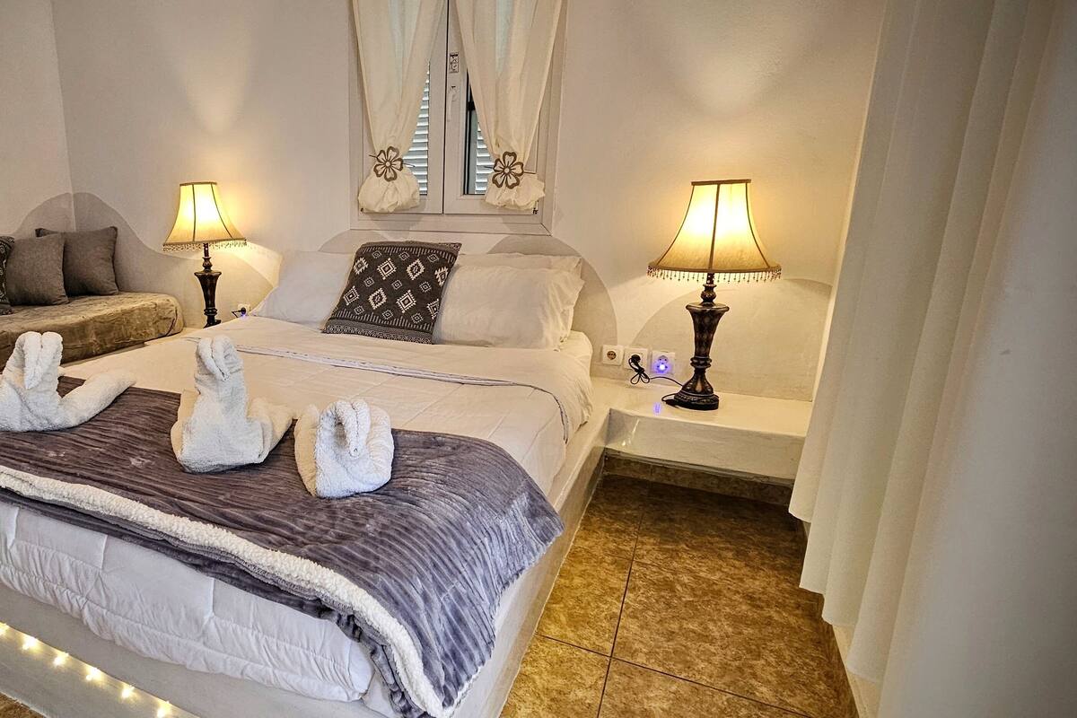 A hotel room with a bed, two bedside tables, a sofa, and two lamps.