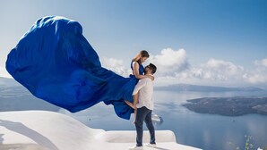 Una pareja abrazándose en una estructura blanca con vista a un lago y tierras lejanas.