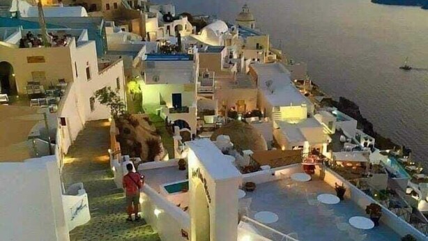 Un pueblo costero con edificios blancos, una zona de piscina y vistas al mar.