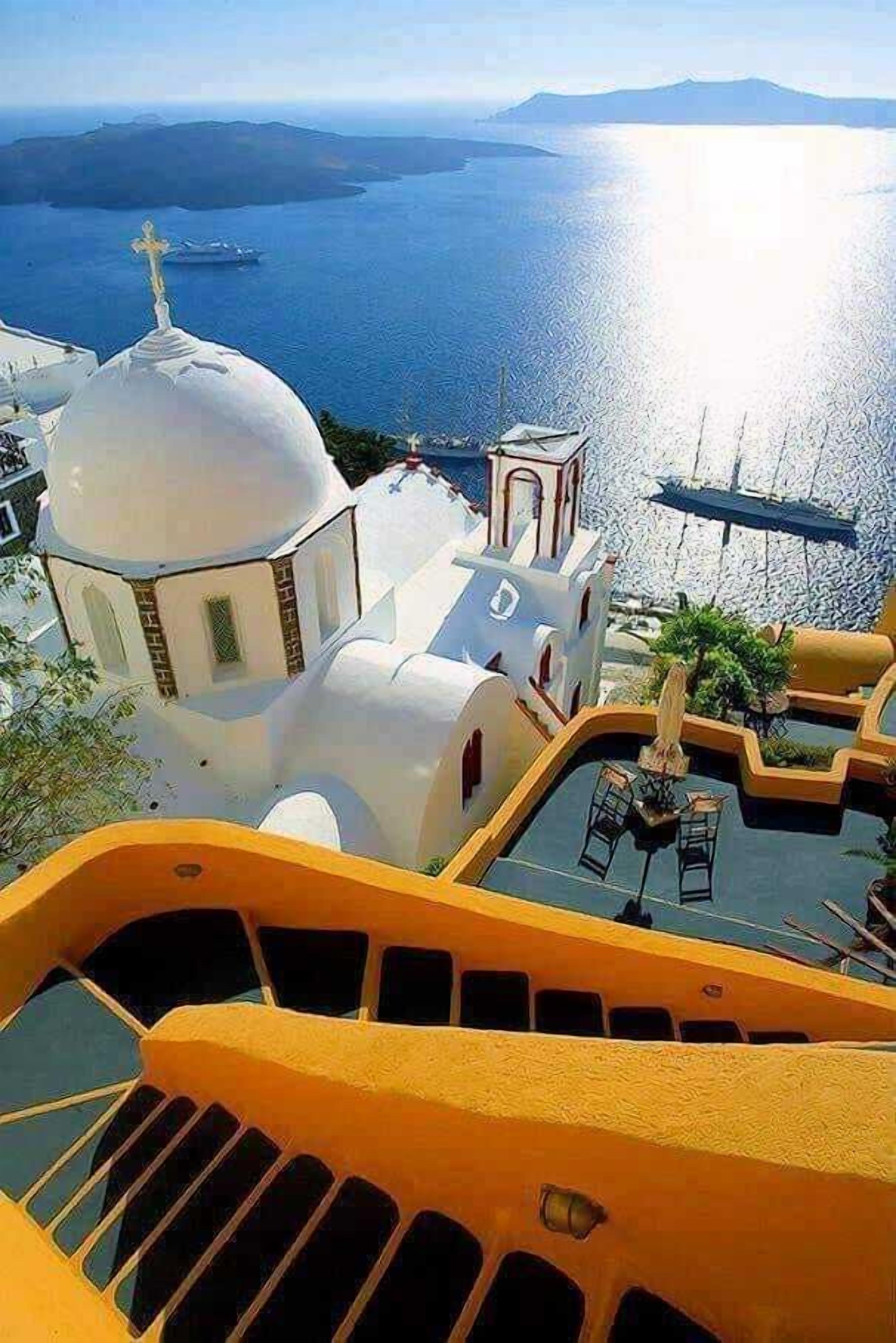 Un bâtiment blanc doté d’un dôme et d’un clocher, qui surplombe une étendue d’eau et une île lointaine.