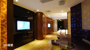 A hotel room with a TV, a bed, a seating area, and a wall with circular designs. - CHIMEI Hotel (Taoyuan City)