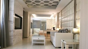 A modern living room with a sofa, a coffee table, and a TV mounted on the wall. - CHIMEI Hotel (Taoyuan City)