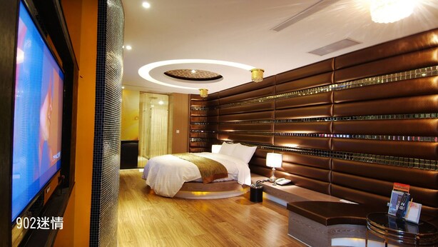 A modern hotel room with a large bed, a TV, and a minibar. - CHIMEI Hotel (Taoyuan City)