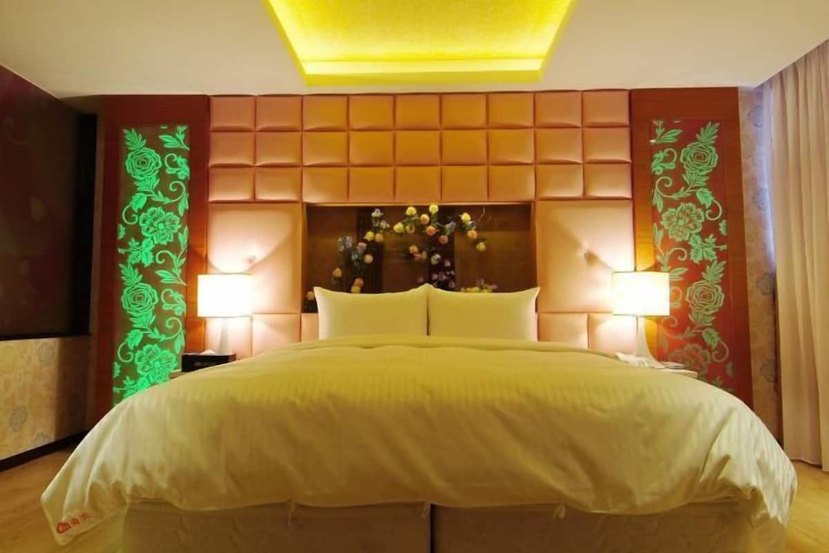 Habitació d'hotel amb un llit gran, un panell de capçal amb folrar i panells decoratius a la paret.