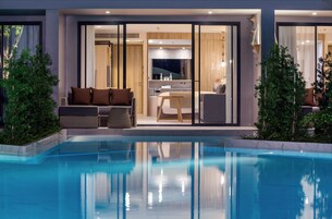 A modern hotel with a swimming pool, a dining area, and a living room with a sofa and chairs.