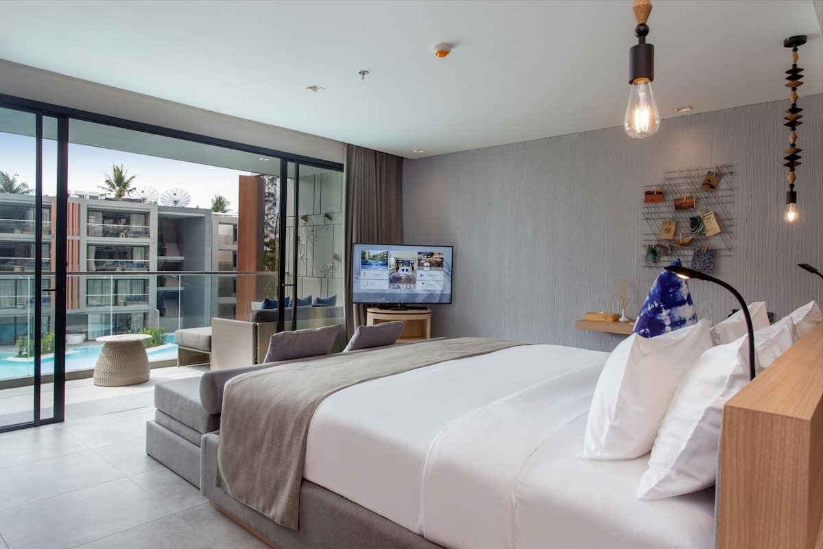 Une chambre d’hôtel moderne dotée d’un grand lit, d’une télévision, d’un balcon avec vue sur la piscine et d’une étagère murale agrémentée d’objets décoratifs.