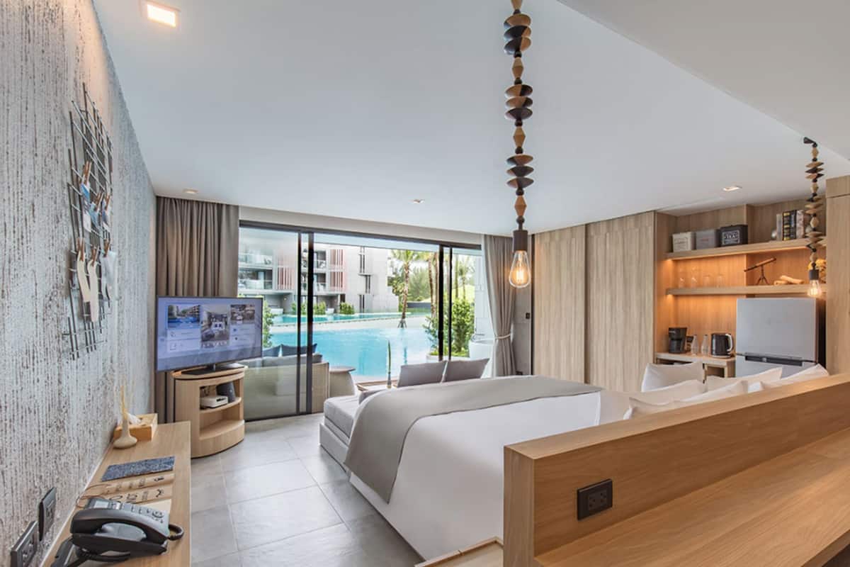 Une chambre d’hôtel moderne dotée d’un grand lit, d’une télévision, d’un bureau avec un téléphone et offrant une vue sur une piscine.