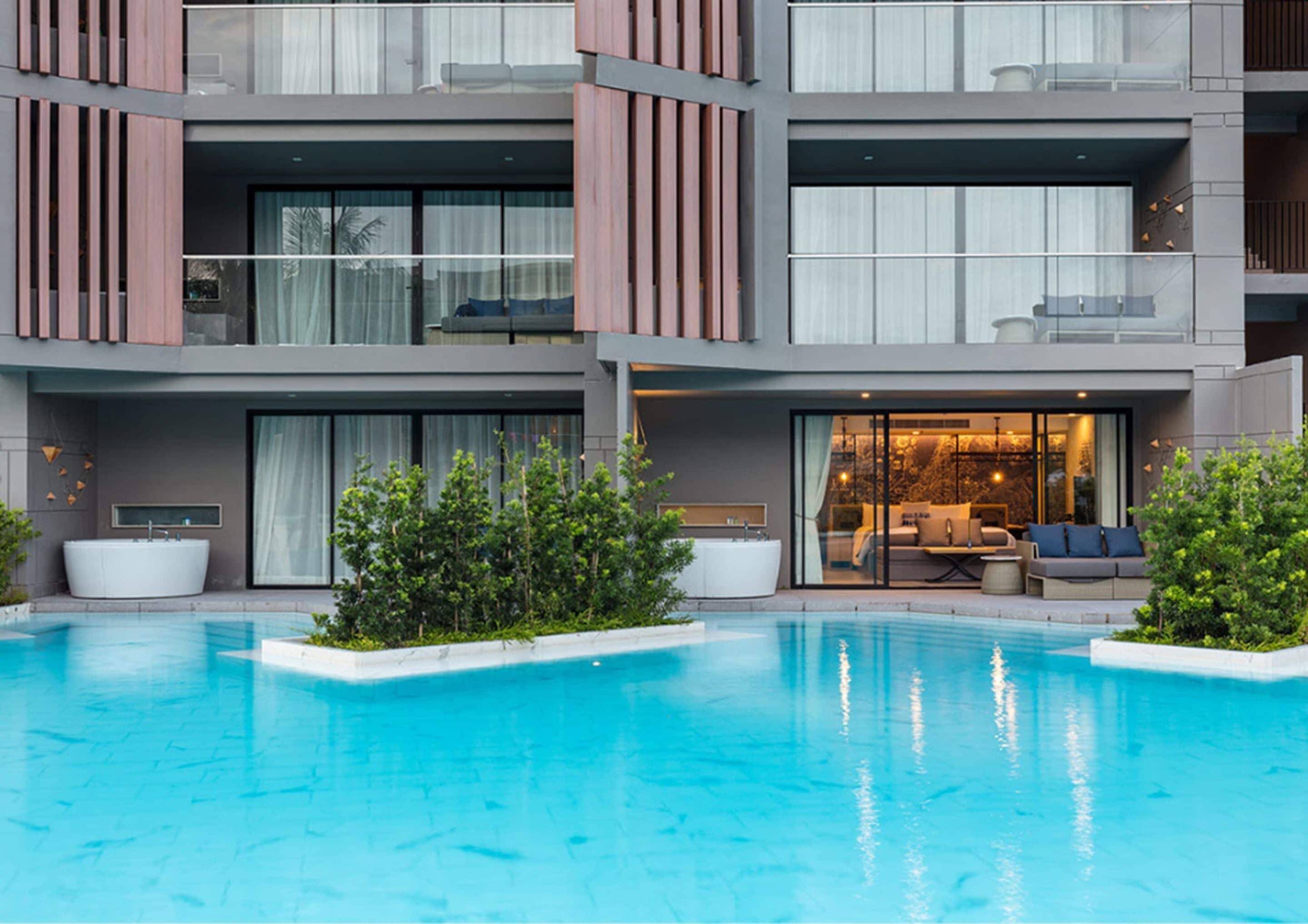 A modern hotel with a swimming pool, outdoor seating, and a well-maintained garden.