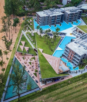 Vue aérienne d’un complexe hôtelier doté de plusieurs piscines, d’une cour centrale et de bâtiments environnants.
