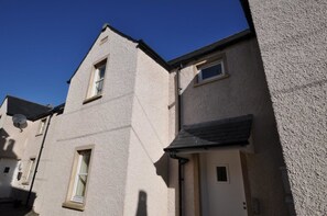 A corner of a building with a beige exterior, a black awning, and a small window. - 6 Varis Apartments (Forres)