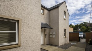 A residential building with a textured exterior, a garage door, and a small entryway with a door. - 6 Varis Apartments (Forres)