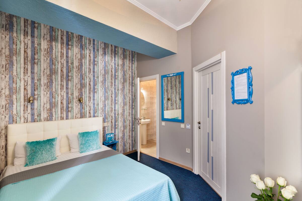 Un dormitorio con una cama, una mesita de noche, un espejo y una puerta que da al baño.