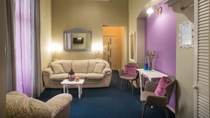 Een woonkamer met een beige bank, een kleine tafel en een paars accentmuur.
