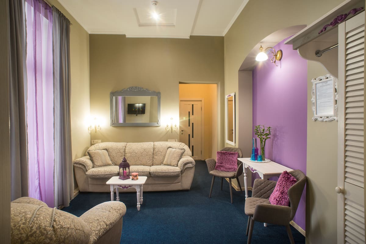 Una sala de estar con un sofá color beige, una mesita y una pared de acento morada.