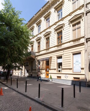 Een historisch gebouw met een klassiek gevelontwerp, een opvallende ingang en een bord dat aangeeft dat het een hotel is.