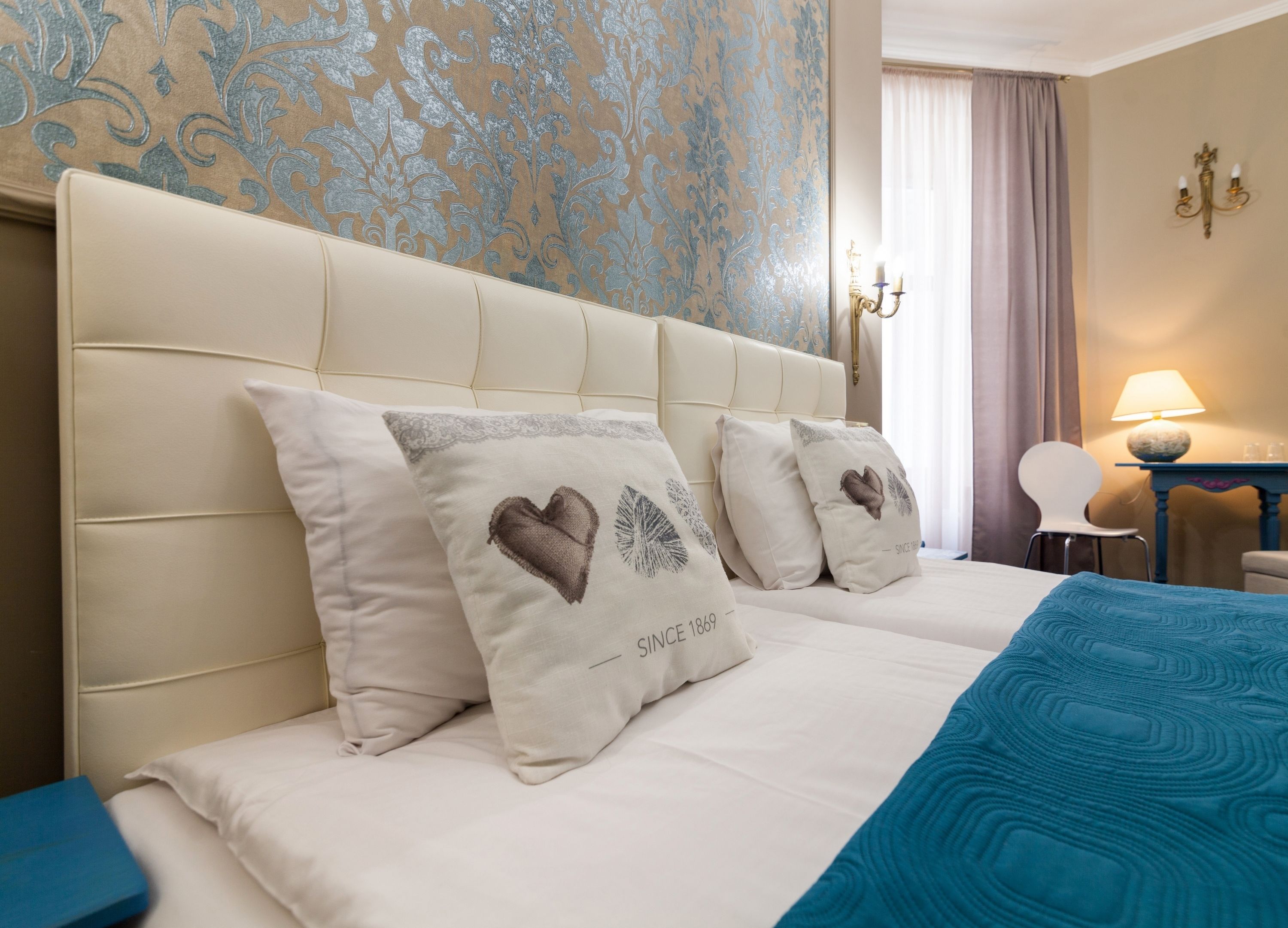 Una habitación de hotel con una cama grande, una colcha azul y cojines decorativos.