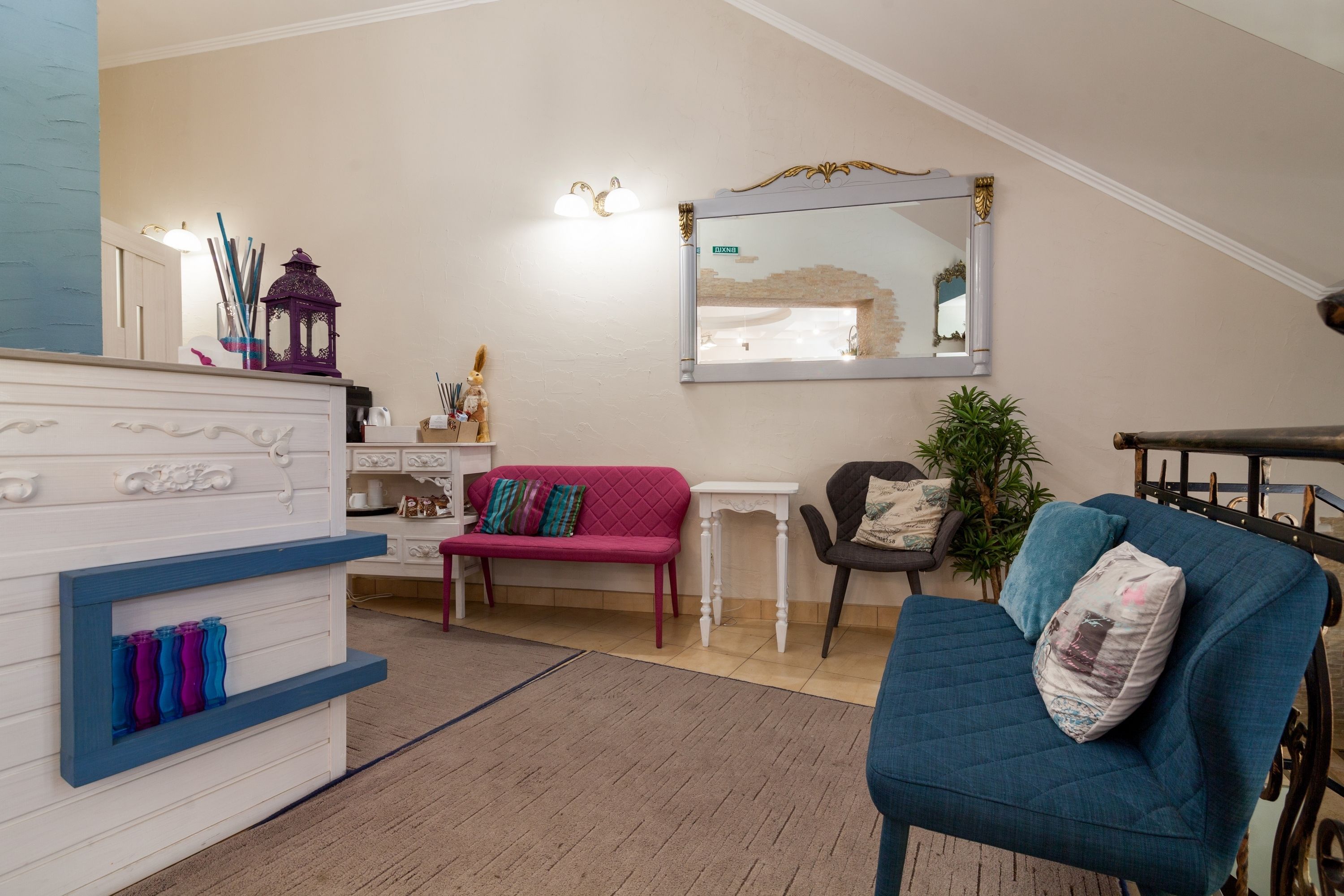 A living room with a blue sofa, a pink sofa, a white dresser, and a mirror on the wall.