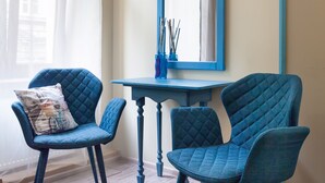 Een kamer met twee blauwe fauteuils, een klein tafeltje en een spiegel met blauwe lijst.