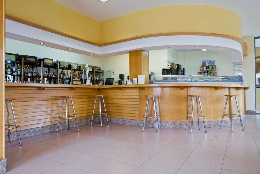 A bar area with a curved counter, four stools, and various bar equipment.
