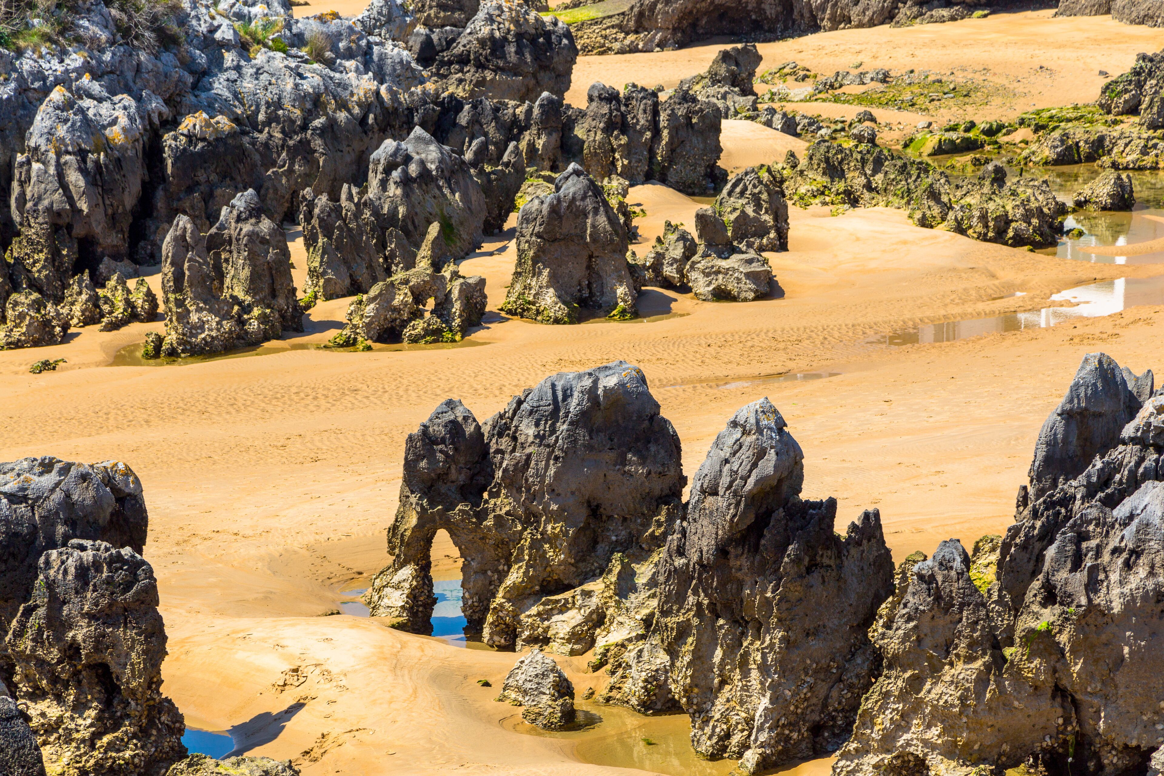 Un paisaje costero con formaciones rocosas destacadas y una playa de arena.