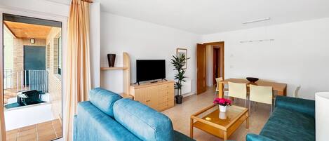 A modern living room with a blue sofa, a wooden coffee table, and a TV.