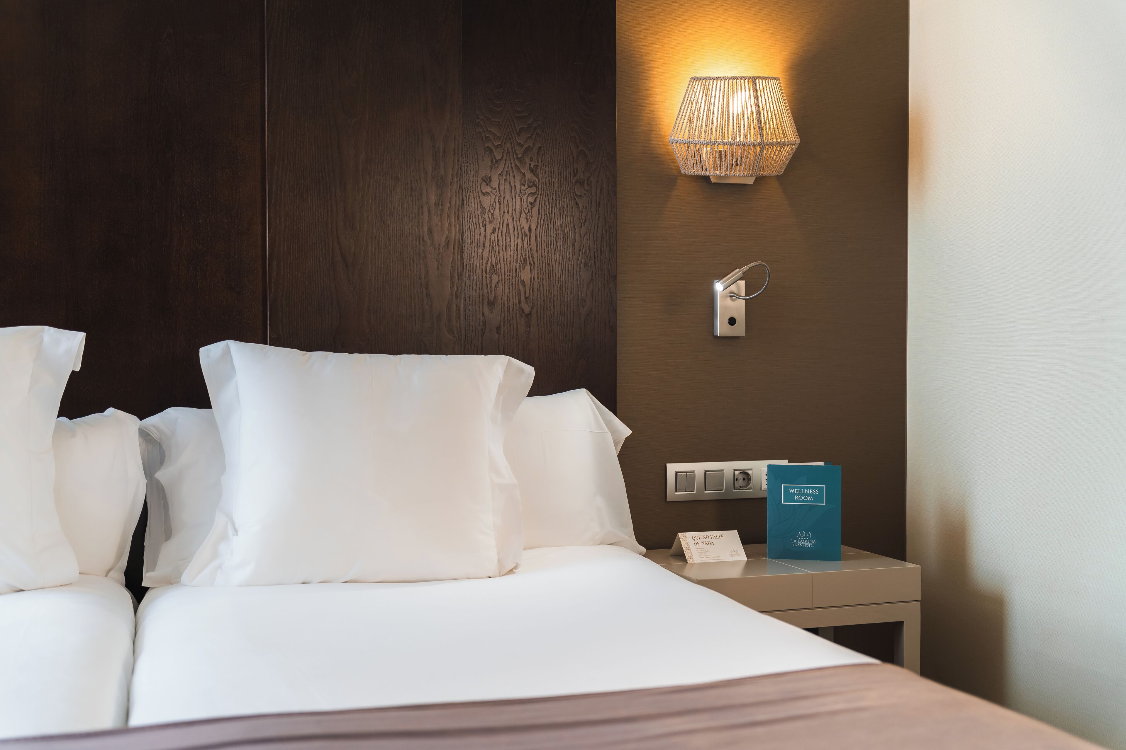 Une chambre d’hôtel avec un lit bien fait, une lampe de chevet, une table de chevet et un panneau indiquant qu’il s’agit d’une salle dédiée au bien-être.