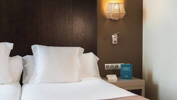 Ein Hotelzimmer mit einem ordentlich bezogenen Bett, einer Nachttischlampe, einem Nachttisch und einem Schild, das auf einen Wellnessraum hinweist.