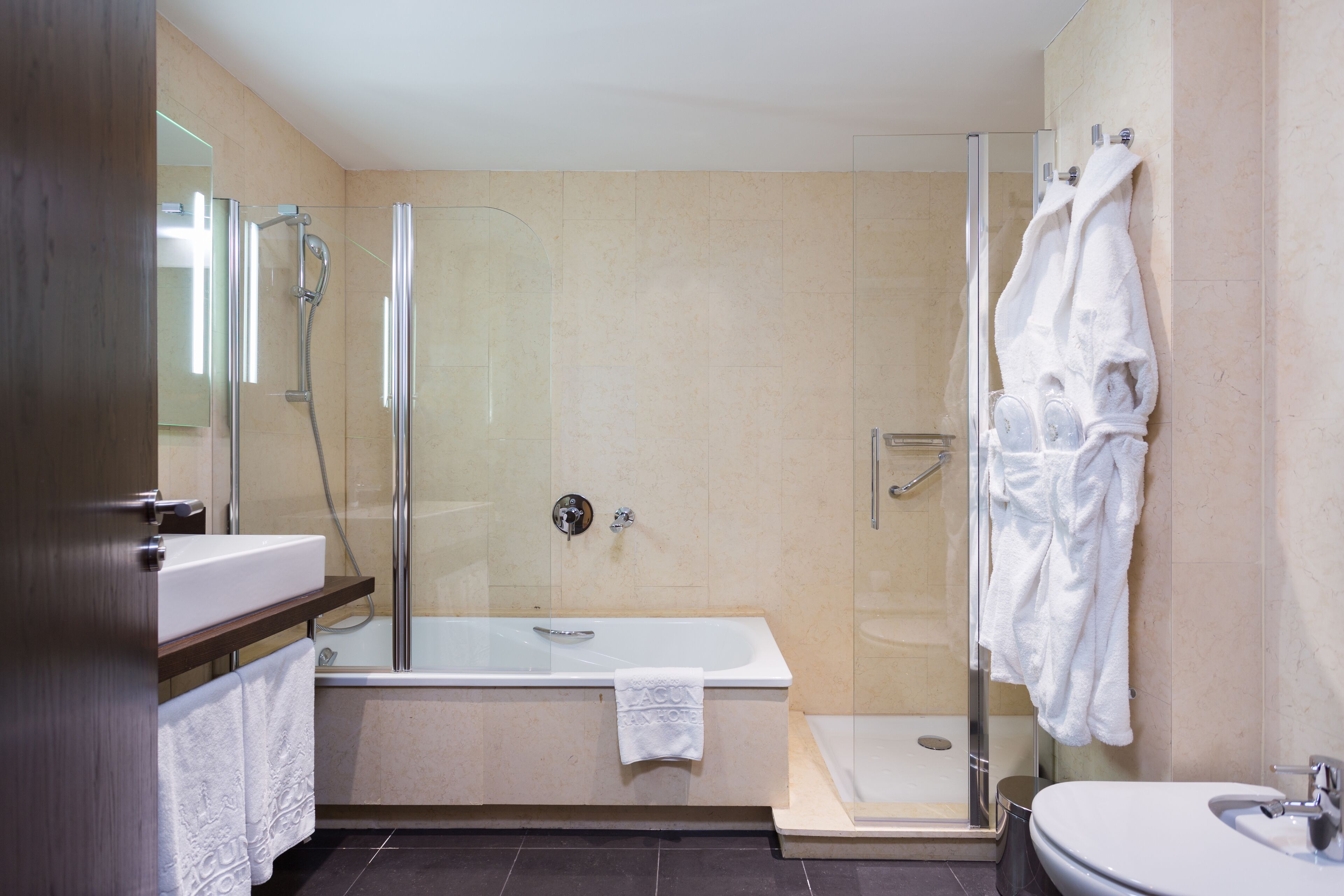 A modern bathroom with a glass-enclosed shower, a standalone bathtub, and a pedestal sink.